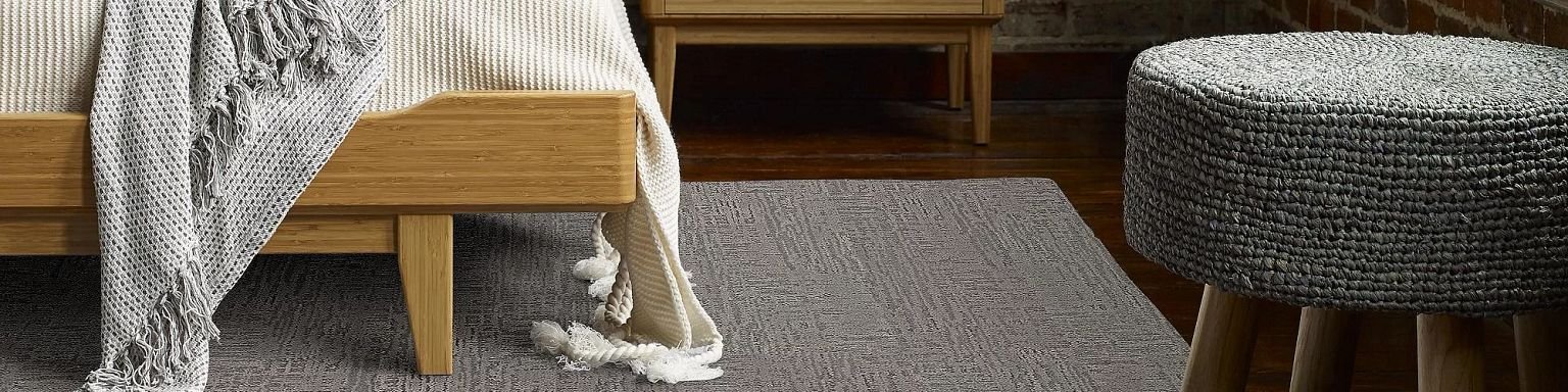 closeup of bed on area rug with small stool - Castillo's Carpet Shack in Riverside, CA